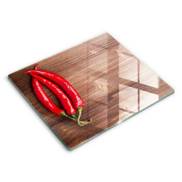 Skärbräda av glas Chilipeppar på trä